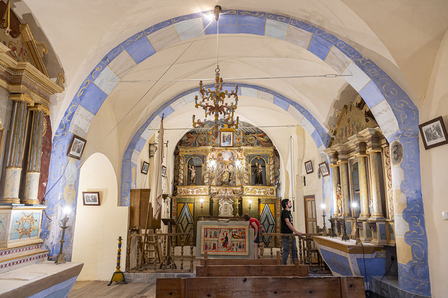 Un noi contempla un dels retaules de l'església de Santa Maria de Cardet i una dona el frontal d'altar. 