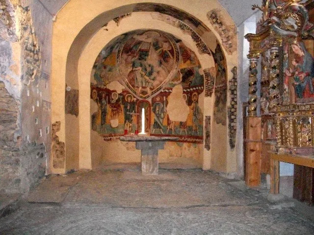 Vista de l'interior de l'església de Santa Maria de Ginestarre amb les pintures murals i un retaule. 