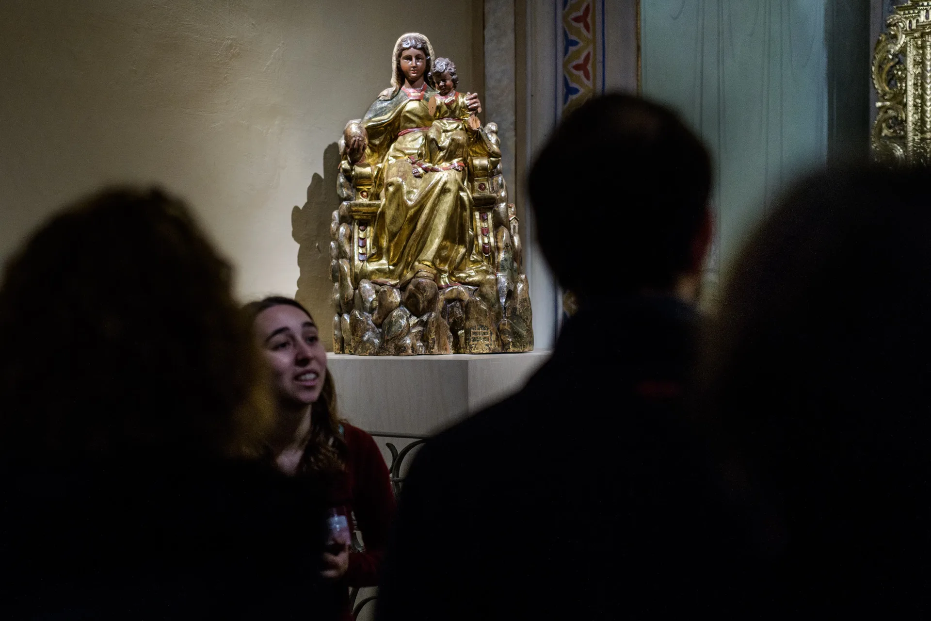 Visita en grup on la guia mostra una escultura de  la Mare de Déu de Montserrat. 