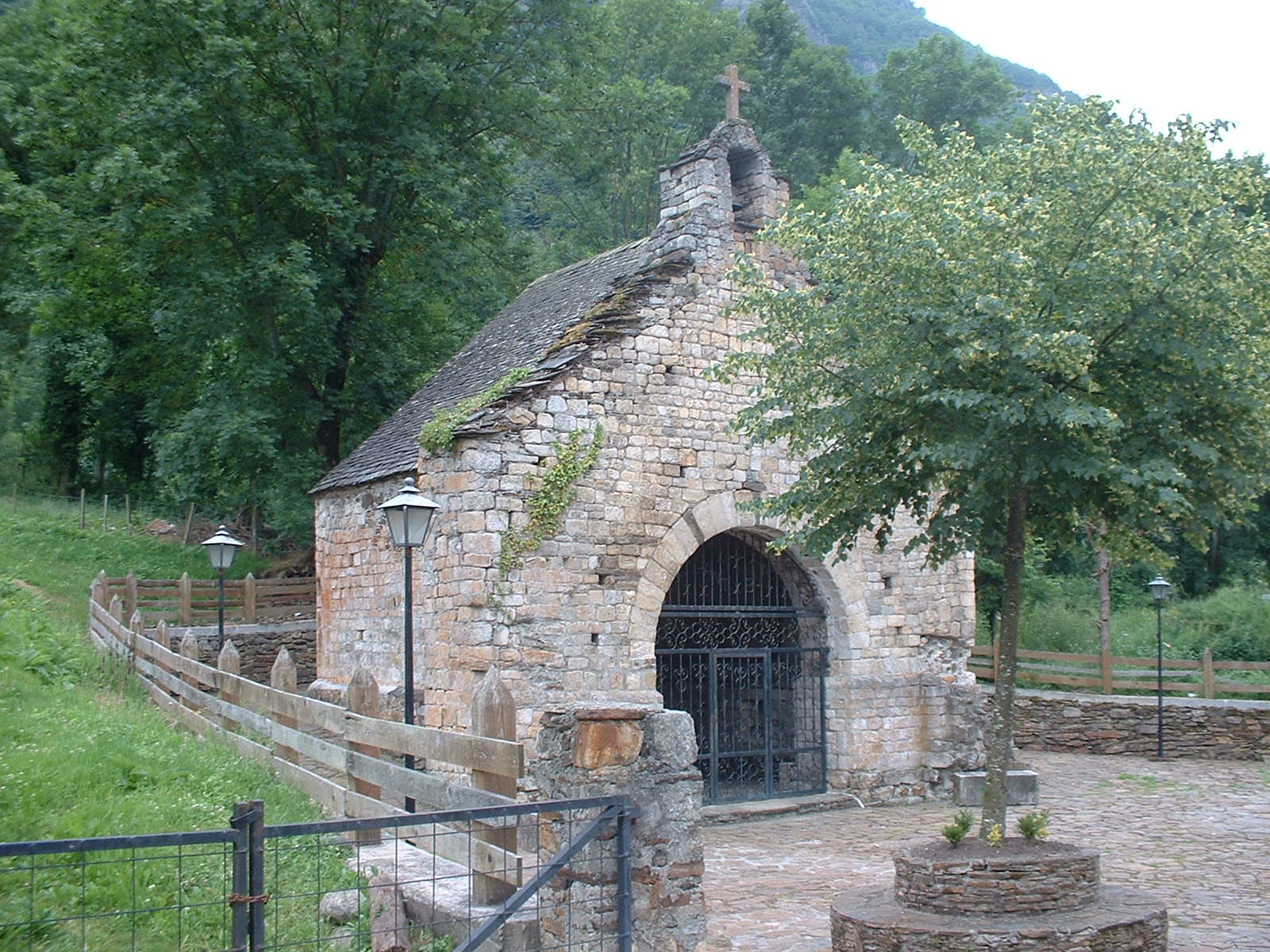 Vista exterior de la petita església romànica de Sant Blai de Les amb un arbre al davant.