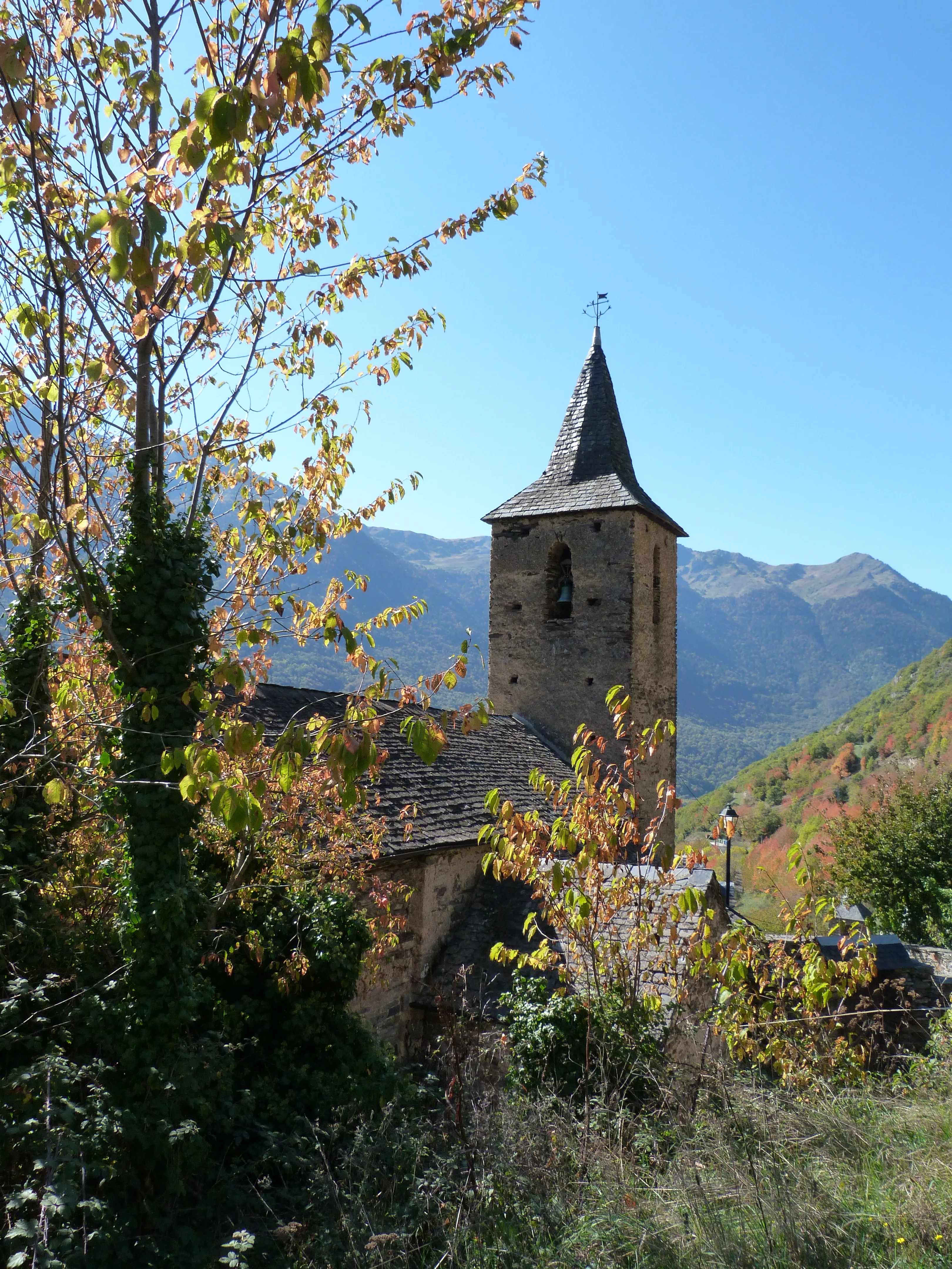 Vista de l'església de Sant Ròc de Begós des de l'exterior amb uns arbres davant. 