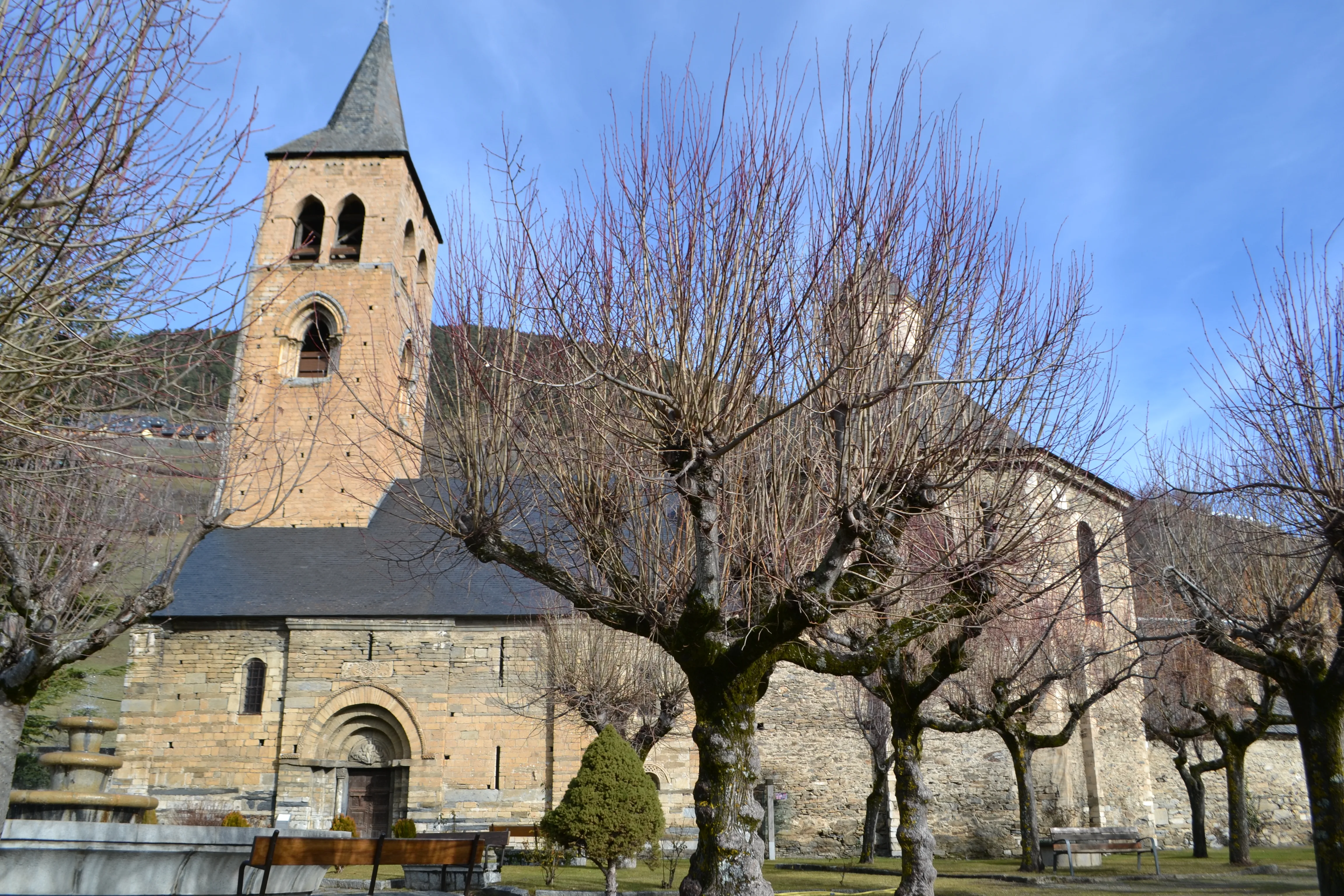 Vista exterior de l'església de Sant Fèlix de Vilac amb tres arbres sense fulles davant. 